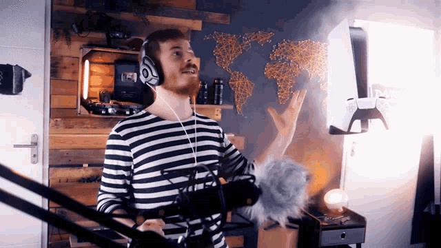 a man wearing headphones stands in front of a microphone in front of a map of the world