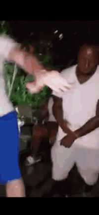 a man in a white shirt and blue shorts is dancing with another man in a white shirt and blue shorts .