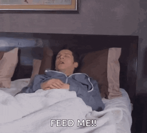 a man is laying in bed with his eyes closed and the words feed me !