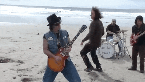 a group of men playing guitars on a beach with a drum that says world