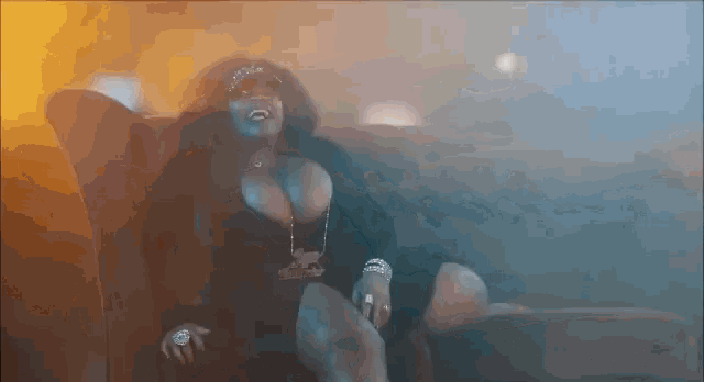 a woman in a black dress is sitting on a couch in a dark room .