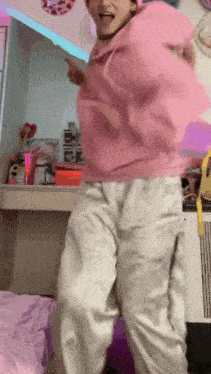 a girl in a pink hoodie and white pants is dancing