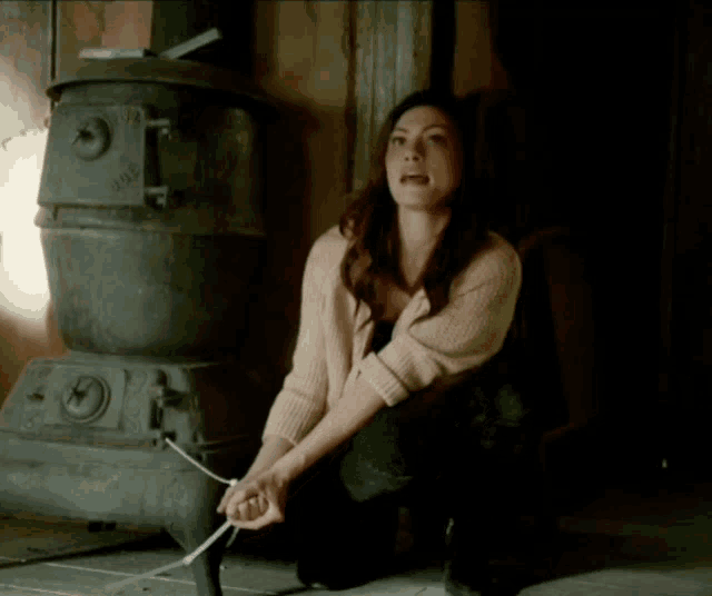 a woman is tied up in front of a stove that says ' johnson ' on the side