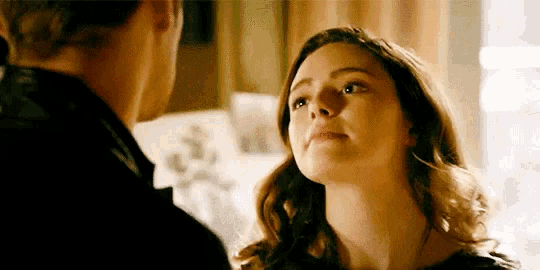 a man and a woman are looking at each other in a room . the woman is looking up at the man .