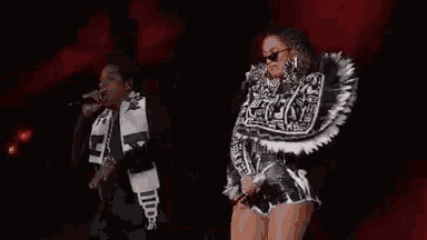 a woman in a black and white outfit is holding a microphone and dancing on a stage .
