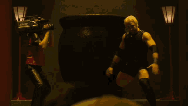 a man with a camera on his head stands next to a wrestler with knee pads