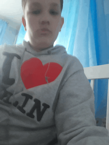 a young boy wearing a grey hoodie that says i love berlin