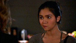 a woman in a grey shirt is looking at the camera