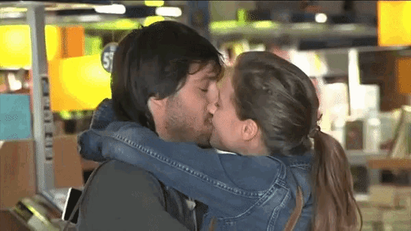 a man and a woman kissing in front of a sign that says 5