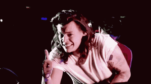 a man with long hair is giving a thumbs up while wearing a white shirt