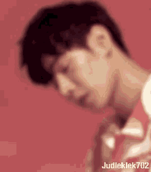 a blurry picture of a young man 's face against a red background .
