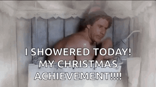 a shirtless man is taking a shower in a bathroom with a christmas message .