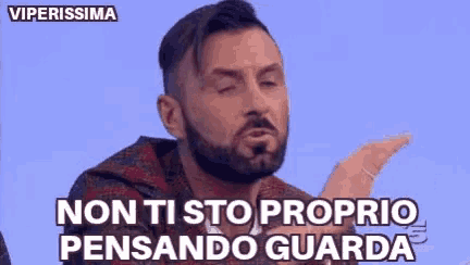 a man with a beard is making a funny face while talking in a foreign language .
