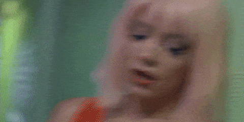 a woman with pink hair and red lipstick is making a funny face .