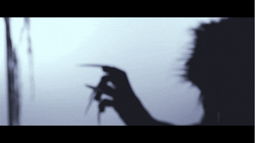 a shadow of a person holding a pair of scissors in their hand