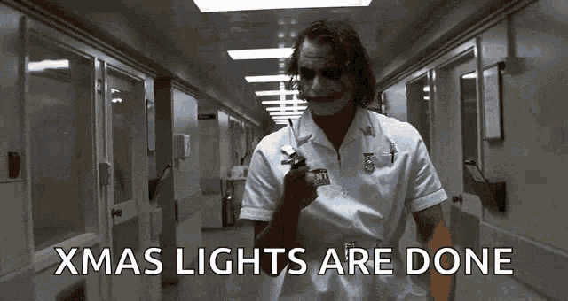 the joker is holding a gun in a hospital hallway and says christmas lights are done .