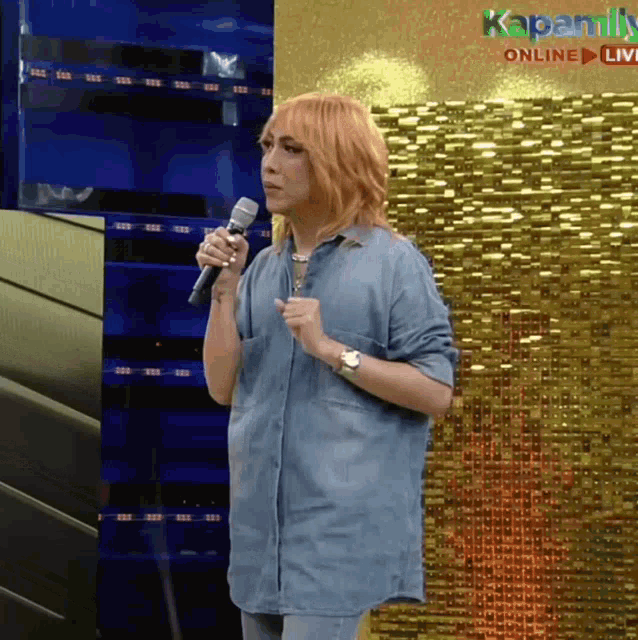a woman with red hair is holding a microphone in front of a sign that says kapamilya online live