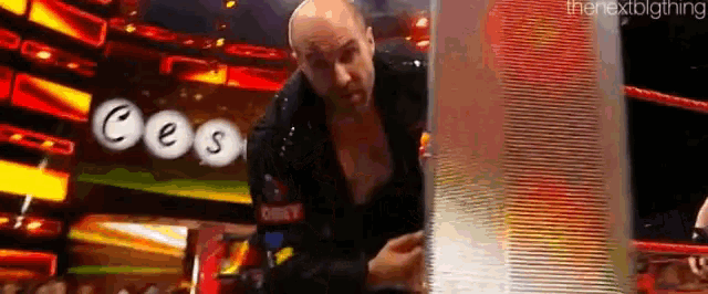 a bald man is standing in a wrestling ring holding a piece of glass .
