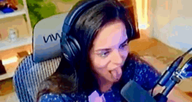 a woman wearing headphones is sticking her tongue out at a microphone .