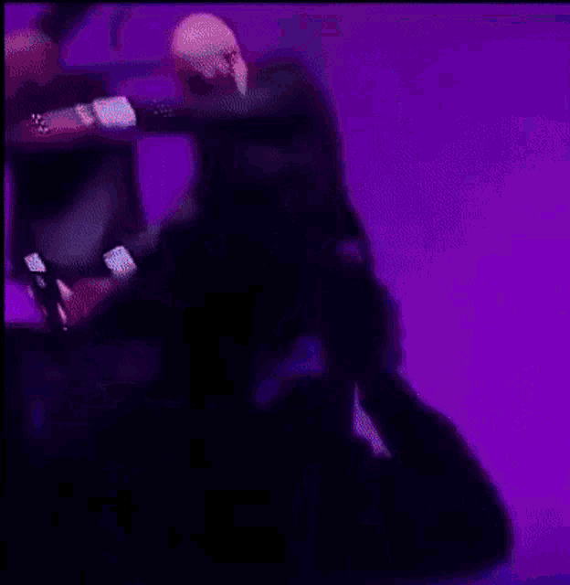 two men in suits are dancing on a stage in front of a purple background
