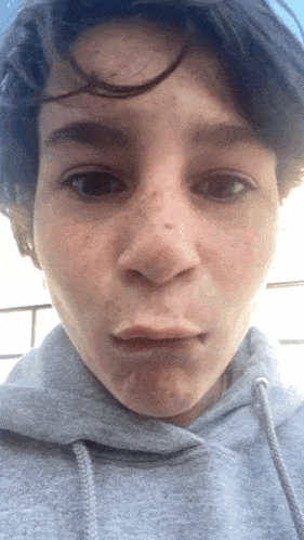 a close up of a person 's face with a gray hoodie