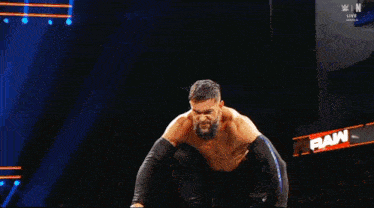 a shirtless wrestler with a beard is dancing in the dark