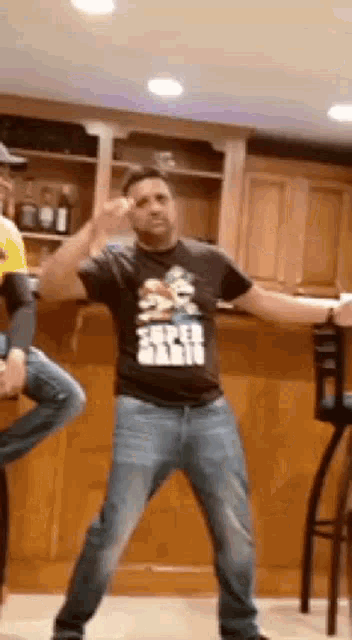 a man wearing a star wars shirt is dancing in a kitchen