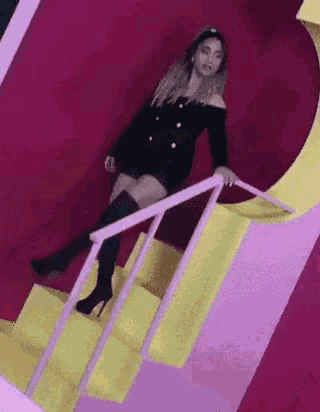 a woman is standing on a set of stairs in front of a pink wall