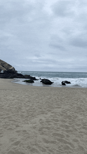 a sandy beach with rocks in the water