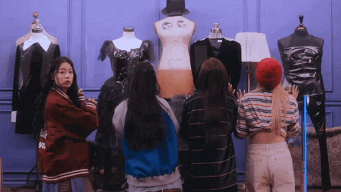 a group of girls are looking at mannequins with one wearing a jacket that says ' abercrombie & fitch ' on it