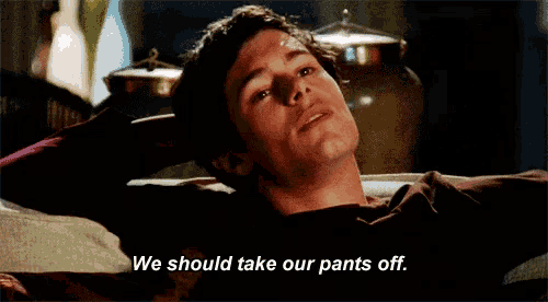 a man is laying on a couch and saying we should take our pants off