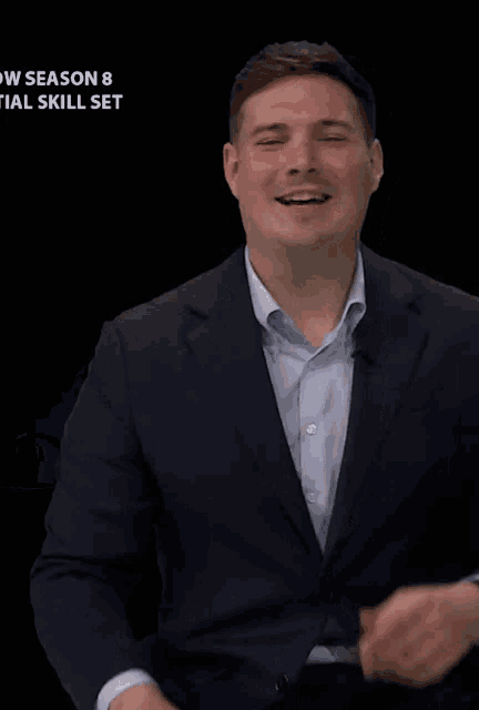 a man in a suit waves his hand in front of a sign that says season 8