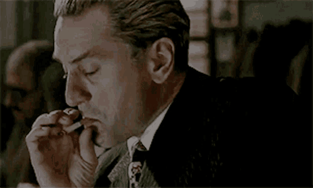 a man in a suit and tie smoking a cigarette