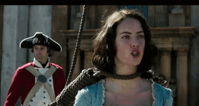 a woman with a rope around her neck is standing next to a man in a hat