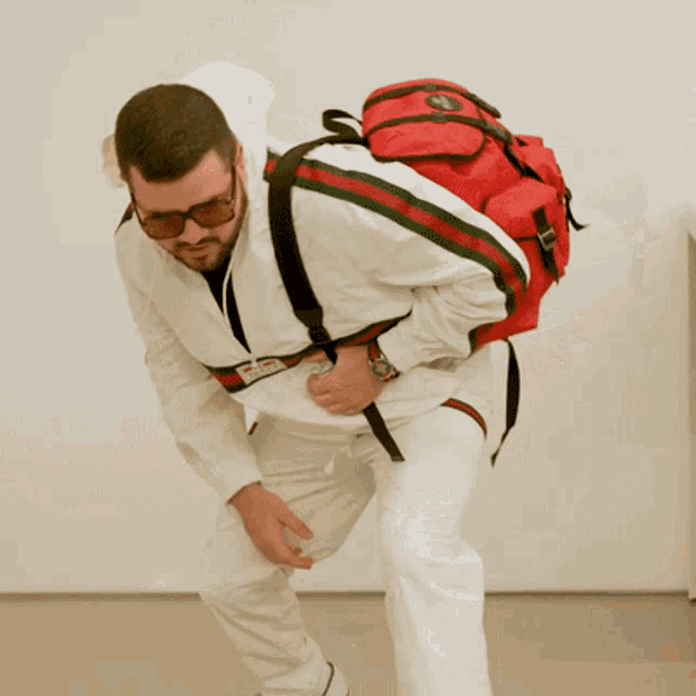 a man wearing sunglasses and a white jacket with a red backpack