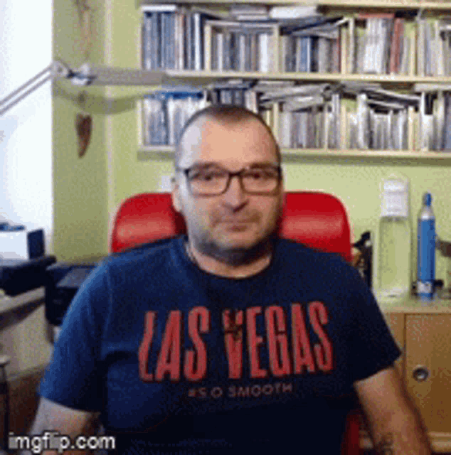 a man wearing a las vegas shirt is sitting in a red chair