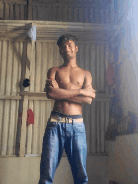 a shirtless man with his arms crossed in a room