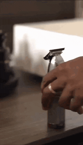 a person with a ring on their finger is holding a bottle of liquid .