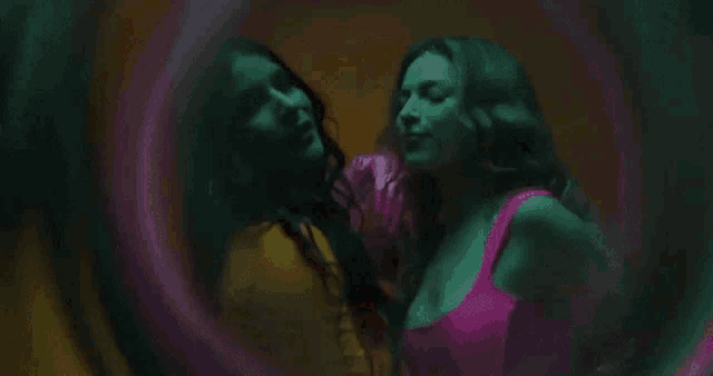 two women are kissing in a dark room .