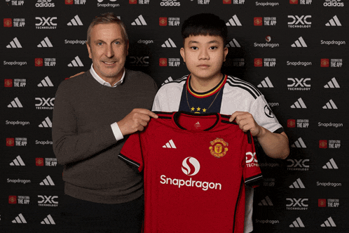 a man and a boy are holding a snapdragon jersey