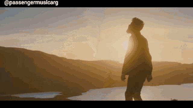 a man is standing on top of a mountain at sunset