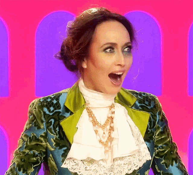a woman wearing a green and blue jacket with ruffles and a white blouse