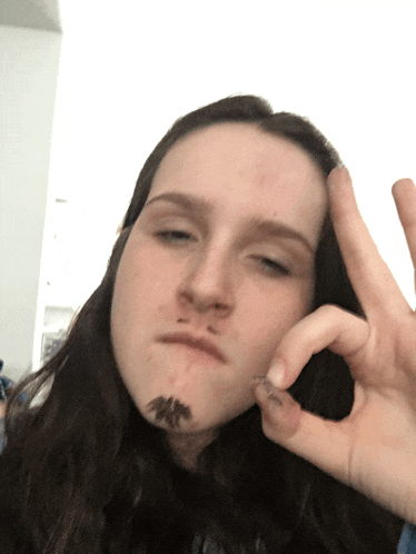 a girl with long hair is making a funny face and holding her hand to her face
