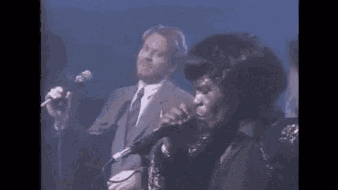 a man and a woman are singing into microphones on stage .