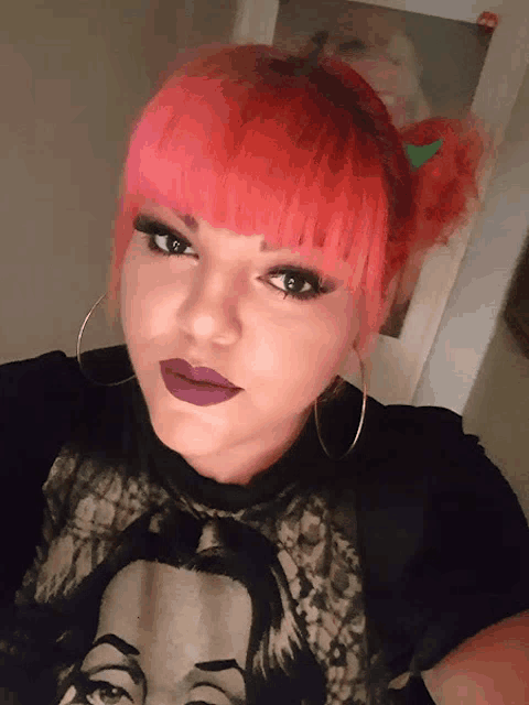 a woman with pink hair is wearing a black shirt