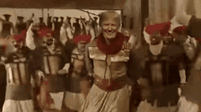 a man in a costume is dancing in front of a group of men in turbans .