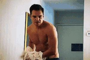 a shirtless man is standing in front of a mirror in a hallway .
