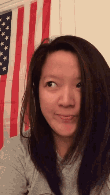 a woman in front of an american flag making a face