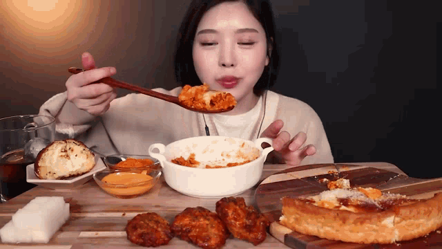 a woman is sitting at a table eating food with a spoon