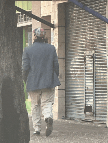 a man in a blue jacket walks down a sidewalk